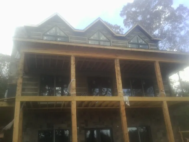 Dormers and porch framing on a large log home under construction — Roof Coating work by our crew in Royal Oak