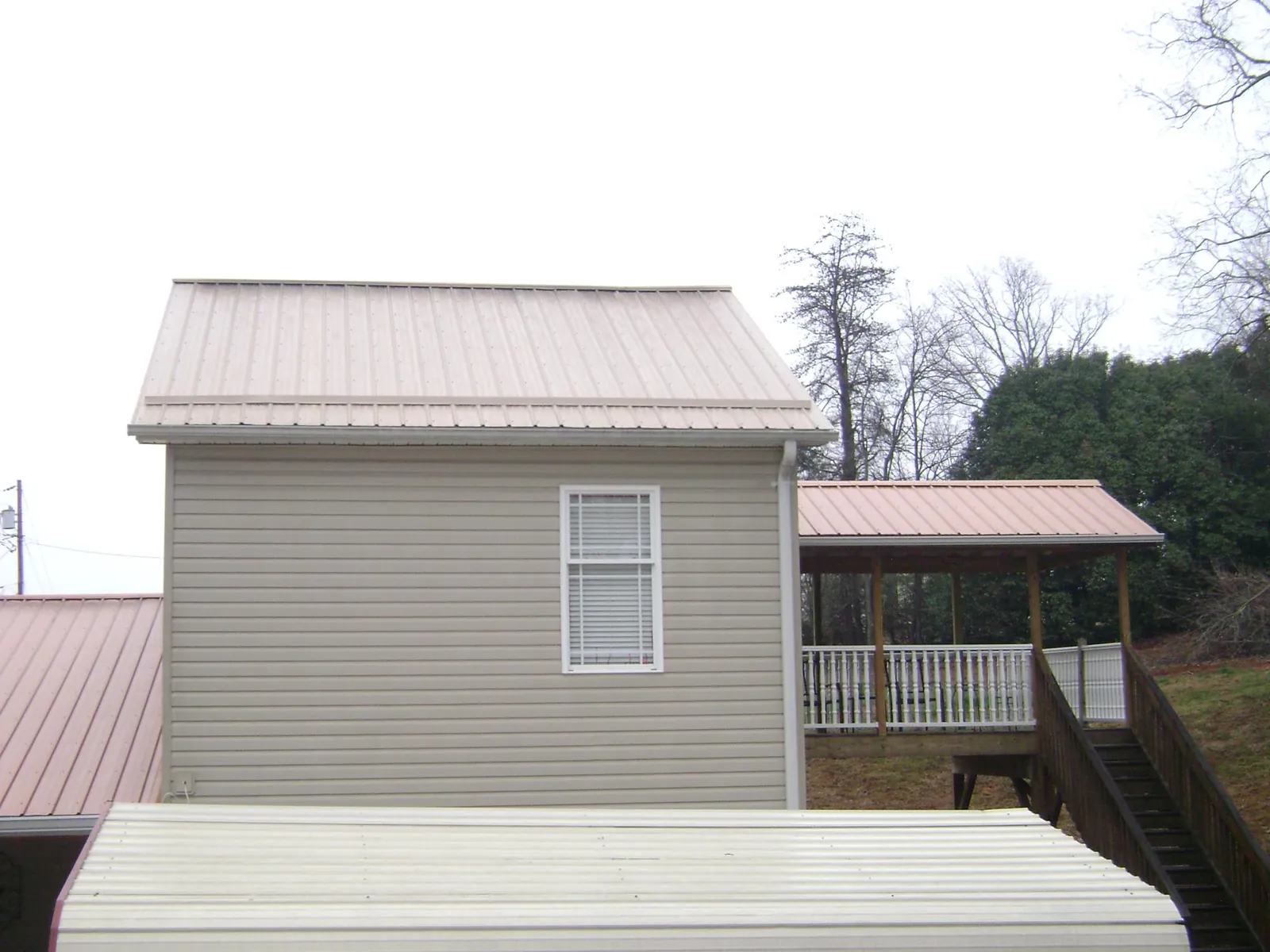 Tan metal roofs on a two story addition and attached porch, from a Roof Replacement job in Royal Oak