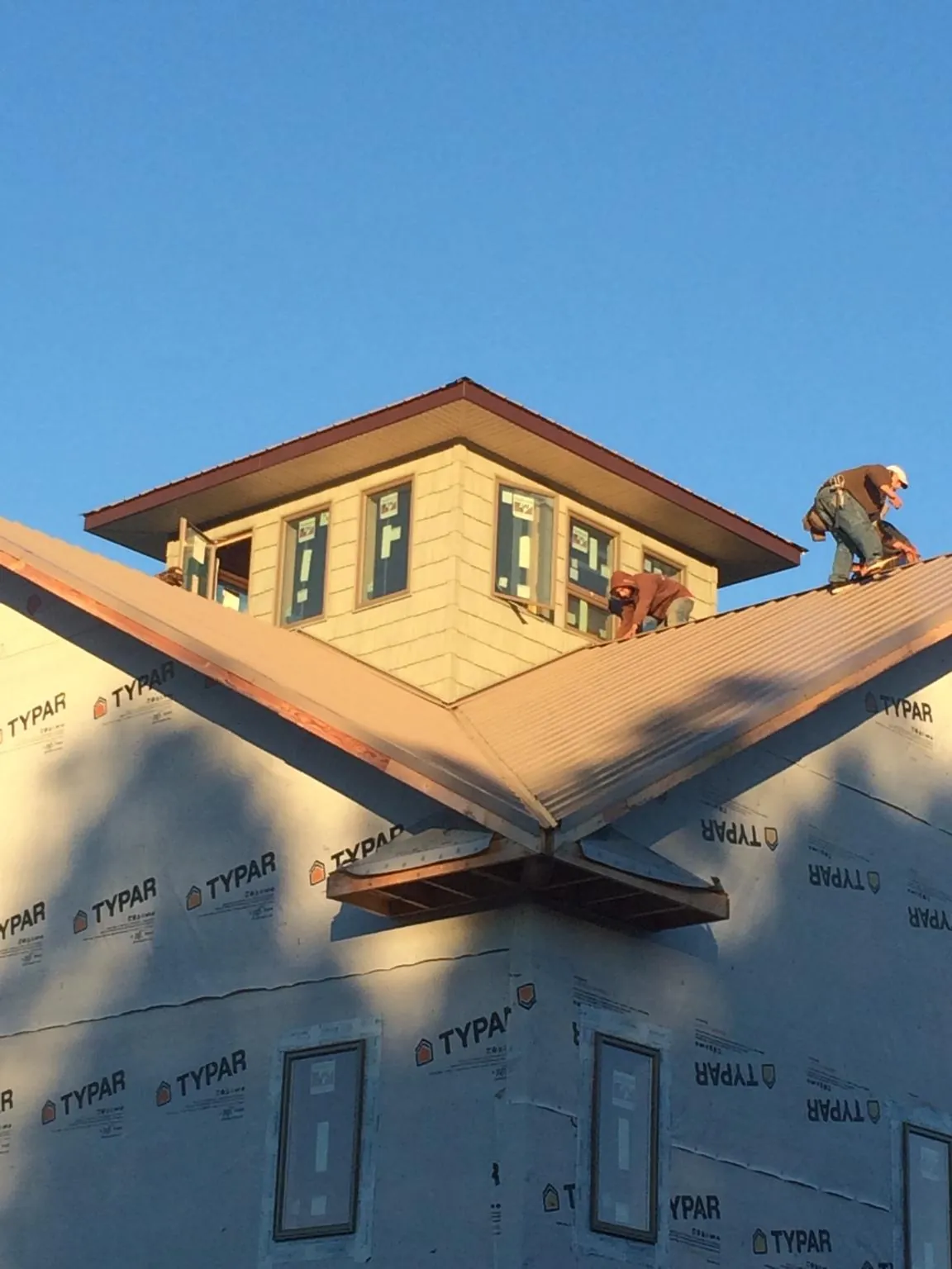 Roofers working around a rooftop cupola on a new metal roof at sunset — Roof Waterproofing in Royal Oak by Roofing Brothers